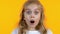 Blonde girl looking extremely shocked hearing news, isolated yellow background