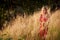 Blonde girl in red dress stand in golden fild