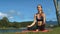 Blonde Girl Relaxes in Yoga Pose on Mat by Lake