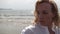 Blonde girl sensually dancing on a background of the sea in white clothes