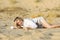 Blonde girl in a shorts and  white shirt lying on send in the biggest European dessert. Hot summer. Oleshki sand, Kherson region i