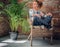 Blonde girl sits on a chair in a room with green palm .