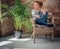 Blonde girl sits on a chair in a room with green palm .