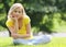 Blonde girl sitting on the grass and smiling. Looking at the camera. Outdoor. Sunny day.