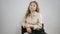 Blonde girl sitting on a high chair. Model posing for a photographer