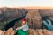 Blonde girl sitting Horseshoe Bend in Glen Canyon National Recreation Area in early dawn