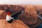 Blonde girl sitting Horseshoe Bend in Glen Canyon National Recreation Area in early dawn