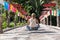 Blonde girl sitting in the middle of a wooden bridge with coloured umbrellas