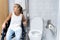 Blonde girl sitting in a wheelchair next to a toilet