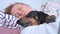 Blonde girl sleeps with cute dachshund in her arms, close up. Owner spends lazy weekend with beloved dog. Permissiveness