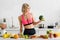 Blonde girl in sportswear holding green broccoli in kitchen