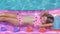 Blonde girl swims in the pool on an inflatable mattress