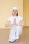 Blonde girl in white practicing yoga in the position Ardha Padmasana