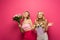 Blonde girls holding floral bouquets on pink background