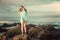 Blonde in green jersey standing on a rock on the beach