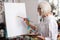 Blonde-haired retired woman painting with yellow gouache