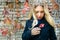 Blonde haired young woman is holding heart shaped red colored autumn leaf