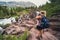 Blonde hiker woman takes photos at Redrock Falls along Swiftcurrent Pass hiking trail in Glacier National Park USA