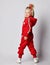 Blonde kid girl in red jumpsuit with hood and cool hairstyle stands back to us and turned. Back view. Full-growth.