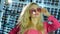 Blonde lady with makeup in pink suit and sunglasses in store