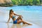 Blonde lady sitting in water on the beach