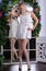 Blonde legged photomodel in white minidress and white stockings posing in studio