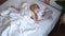 Blonde little girl sleeping in big bed with white bedding. Top view. Children dream. Childhood, calm, night. 4k footage.