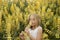 Blonde little girl smelling yellow wildflowers