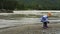 Blonde little girl throw stones in the river.