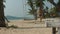 A blonde with long hair in a swimsuit gets up from a swing hanging from a palm tree and walks along the white sand to