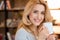 Blonde mature woman drinking tea and smiling at camera