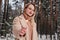 Blonde mid age woman in winter forest with sparkler in hand. Woman in coat and sweater outdoors. Girl in eyeglasses