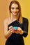 Blonde model in black dress is smiling, showing handful of multicolored chips, posing on colorful background. Poker