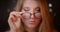 Blonde model with bright make-up fixes her eye-glasses flirting with camera on bokeh background.