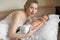 Blonde mom and her newborn baby lie on the bed