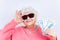 blonde old lady wear pinl sweater and sunglasses showing money isolated white background