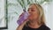 Blonde overweight woman drinks water from a bottle after fitness training