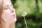 The blonde in park with a dandelion in hands