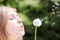 The blonde in park with a dandelion in hands