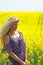 Blonde peasant girl in floral print dress on the rapeseed field