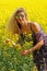 Blonde peasant girl in floral print dress on the rapeseed field