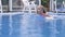 Blonde in a pink swimsuit swims in a pool with clear blue water