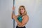 Blonde pole dancer holding on to the pole and looking serious on camera. The girl is wearing a green top. Dancing concept