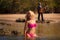 Blonde pretty girl in pink swimsuit sit in shallow