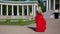 blonde in red dress is walking in garden near palace at summer