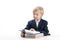 Blonde schoolboy sits at table and flips through textbook. Boy in school uniform reads textbook. Bright student