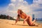 blonde slim girl in bikini crawls one hand up along wet sand