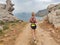 Blonde sport woman in sportwear running on mountain path. Summer vacations in Greece