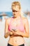 Blonde sportswoman using mobile on beach