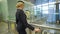 Blonde stewardess standing in waiting room with suitcase in airport